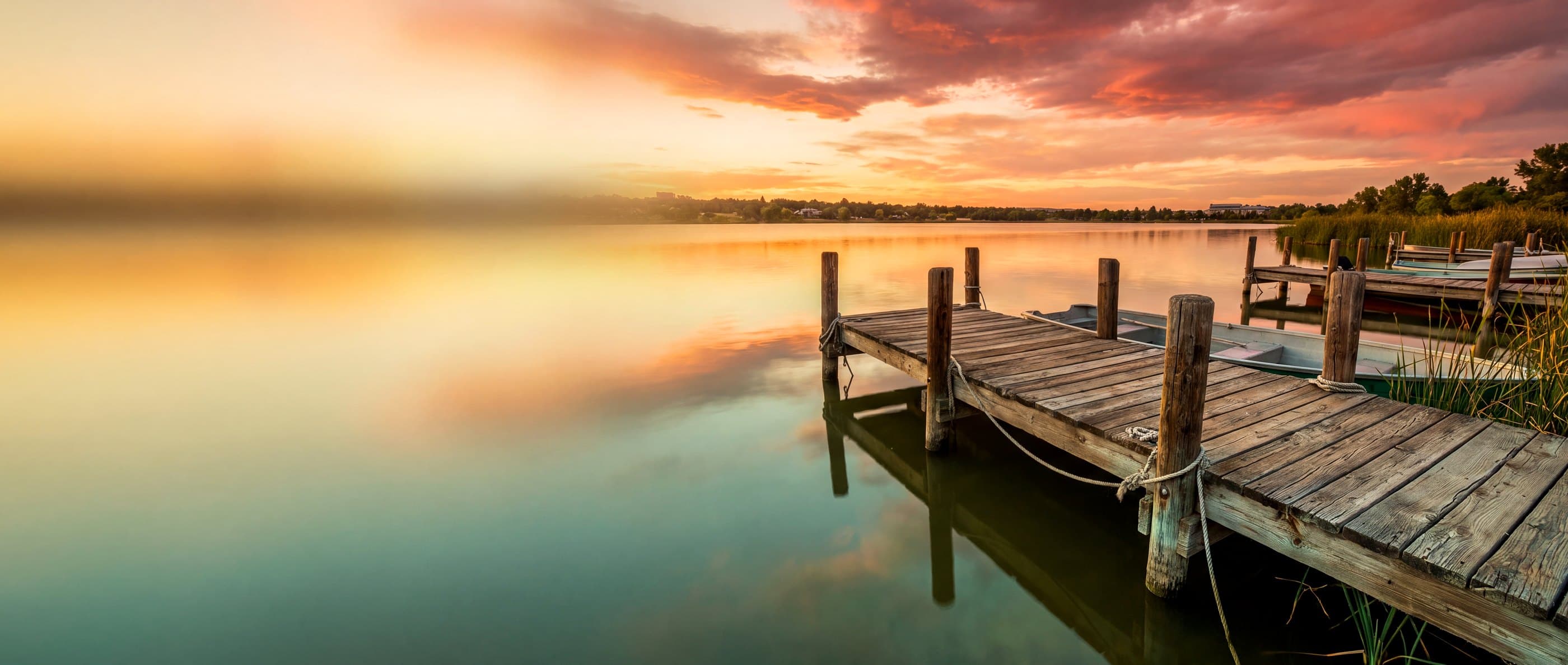 A wooden dock on a calm lake at sunset